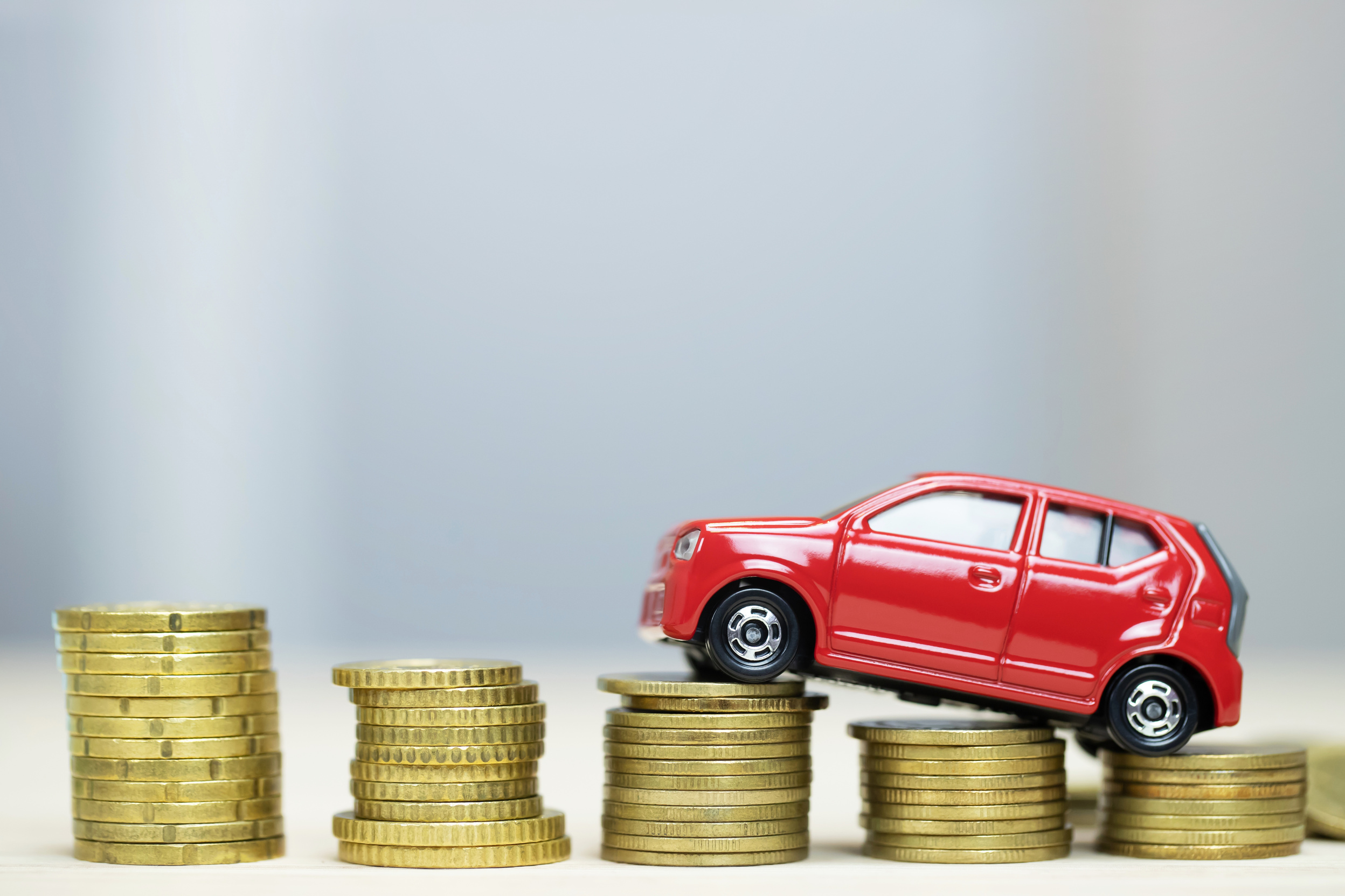 Little red car over a lot of money stacked coins. for bank loans costs finance. insurance, buying car finance concept. buy and pay by installments down payment a car.